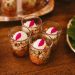 Delightful layered appetizers in glass cups beautifully presented with fresh greens on a wooden table.
